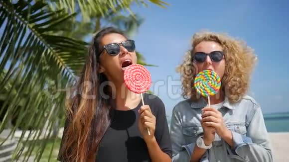 美丽的混合种族海普斯特女孩在热带海滩舔棒棒糖和微笑高清慢速运动戈芬加视频的预览图