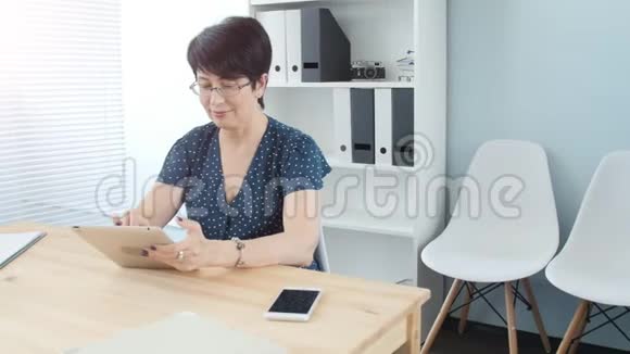 办公室的中年妇女正在制作一块平板电脑视频的预览图