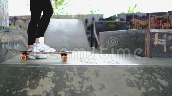 特写一个穿着黑腿的女孩试图骑在滑板或长板上摔倒的镜头视频的预览图
