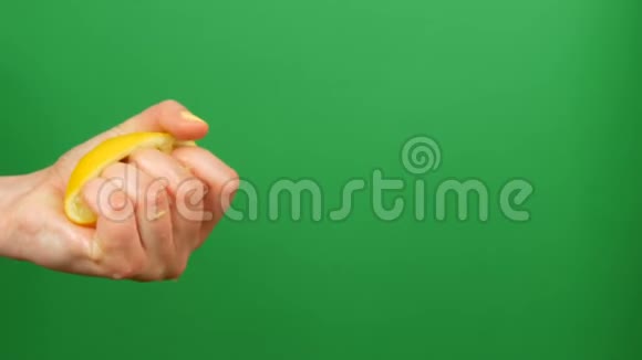 带有黄色指甲的女性手在绿色关键背景上挤出半个柠檬视频的预览图