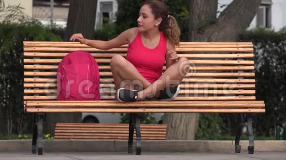 坐在公园长椅上的快乐女学生视频的预览图