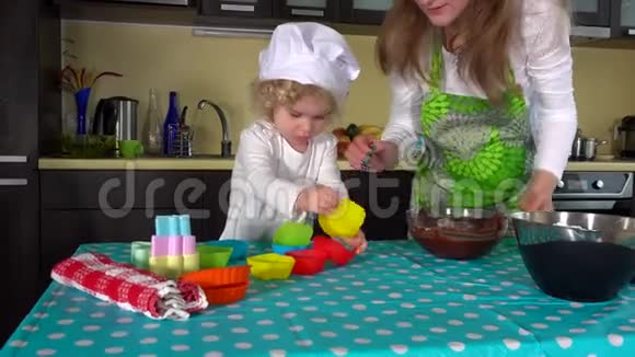 母亲和女儿用手准备桌上的蛋糕面团视频的预览图