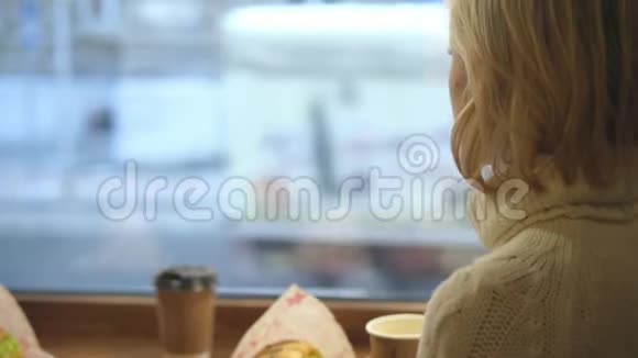 一位年轻女士正在咖啡馆里享用法式早餐咖啡和牛角面包视频的预览图