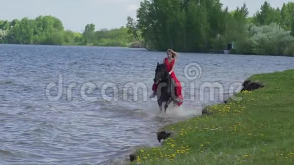 一位美丽的金发女郎穿着红色连衣裙在湖边骑马视频的预览图