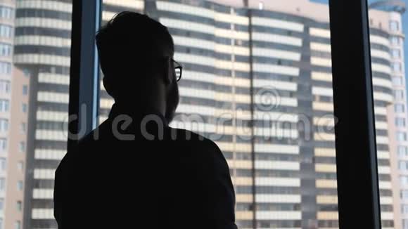年轻的成功商人在一扇窗户的背景上穿上一件夹克在市中心有一种高业务视频的预览图