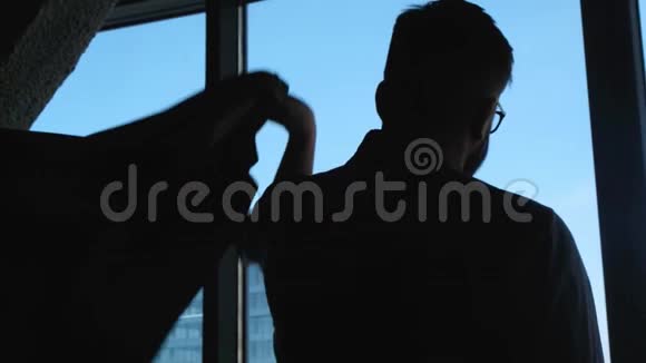 年轻的成功商人在一扇窗户的背景上穿上一件夹克在市中心有一种高业务视频的预览图