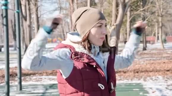 冬天阳光明媚的一天一个运动女孩在运动场上做热身运动的肖像视频的预览图