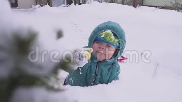 男孩孩子躺在圣诞树附近的雪上在户外玩装饰视频的预览图