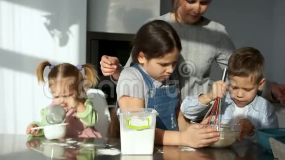 三个不同年龄的孩子揉面团姐姐把面粉放在碗里妈妈在后台管理视频的预览图