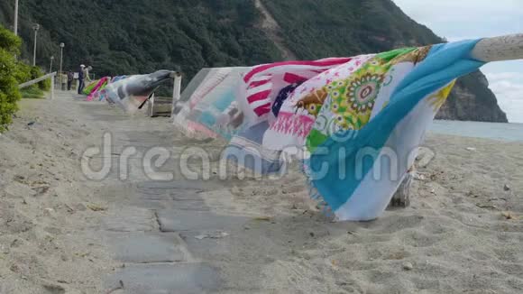 沿着沙滩上的木制护栏走沙滩上挂着摇曳的沙滩毛巾视频的预览图