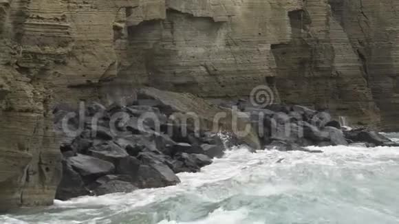 强大的波浪撞击岩石悬崖落下产生泡沫和飞溅视频的预览图