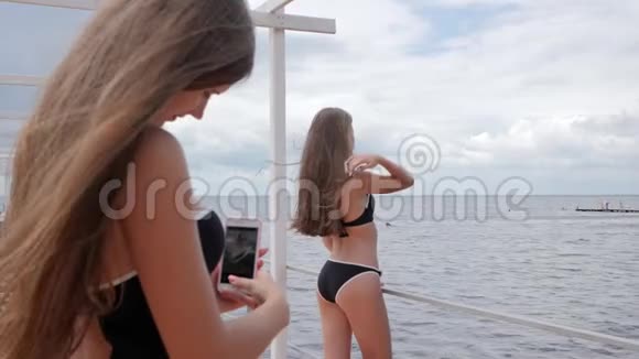 海边穿泳衣的女孩的照片手机水中长头发的女人在智能手机上的照片视频的预览图