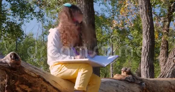 美丽快乐时尚欢乐欧洲可爱的小女孩坐在河边画在桌子上4K视频的预览图
