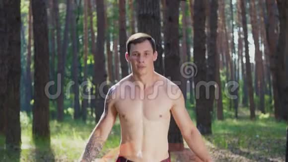 一个年轻的运动员赤裸的躯干跳绳用一根橡皮绳和一根交叉绳做力量练习视频的预览图
