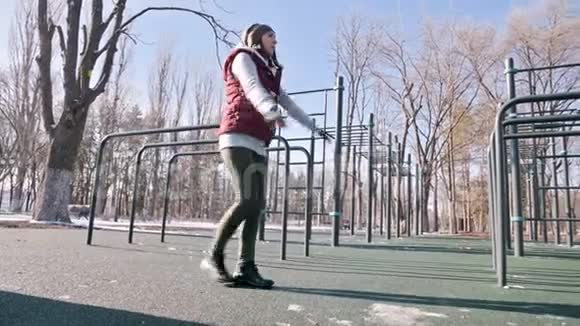 低角度对抗太阳运动女孩在冬天的操场上做弓步大步向前视频的预览图