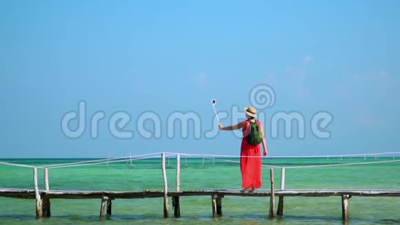 PhuQuoc岛穿红色衣服的女人带着绿色背包在码头上散步旅行者自己在上面拍照视频的预览图