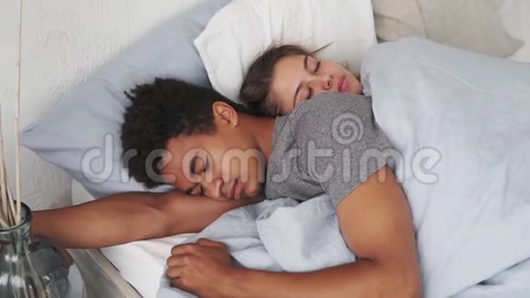 多种族夫妇躺在床上睡觉相互拥抱的特写镜头年轻家庭观念视频的预览图