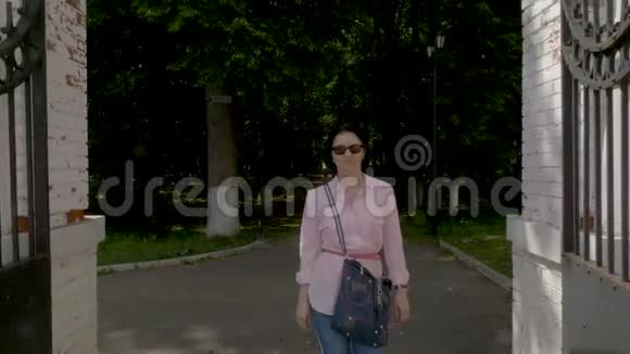 一个戴着太阳镜的中年妇女在公园里慢慢地走着视频的预览图