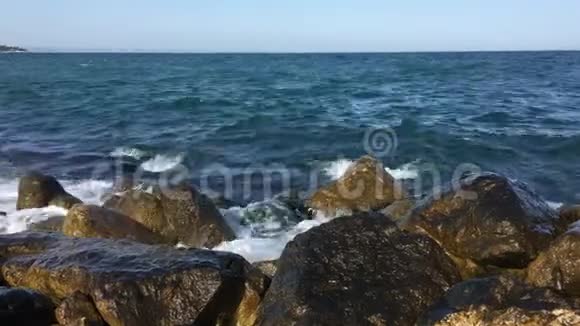 阴天海湾里的海潮一场小小的风暴波兰卡和港口海浪拍打在一块大石头上蓝天云彩和太阳视频的预览图