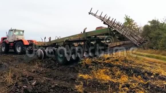拖拉机把犁耕机放到地里耕地视频的预览图