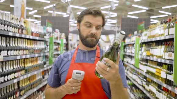 超市员工在超市红酒区用红色笔扫描瓶条形码视频的预览图