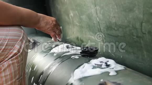 检查一艘绿色橡胶充气船的阀门旧的女性手用肥皂液来检测漏气视频的预览图
