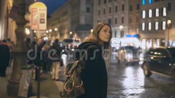 年轻时尚的女人站在市中心独自在晚上的交通道路上环顾四周视频的预览图