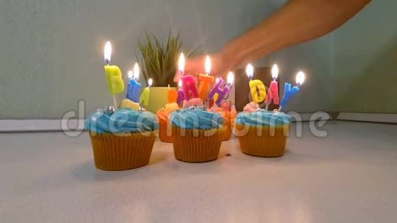 多种颜色的纸杯蛋糕和蜡烛以纪念生日聚会年轻人的手在纸杯蛋糕上点燃蜡烛慢动作视频的预览图