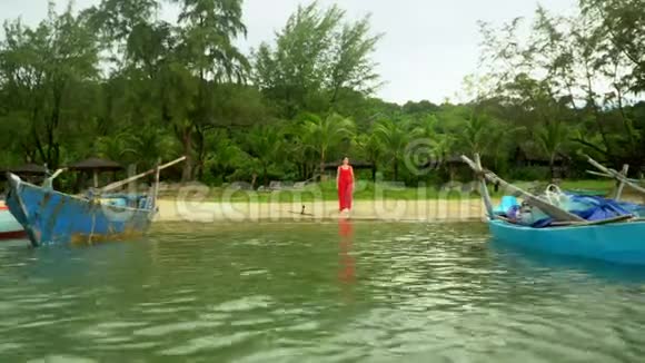 冒险背景岛上海岸的传统蓝色渔船穿着红色裙子的女人走在视频的预览图