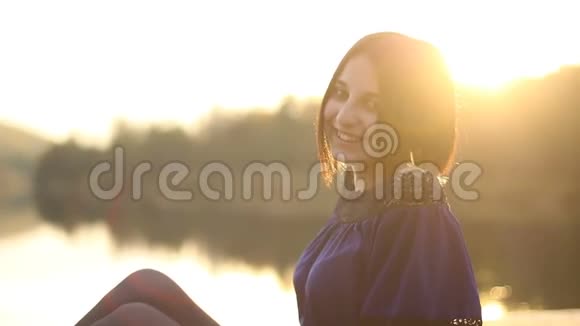 美丽年轻的黑发女人在大自然的夕阳下微笑的肖像视频的预览图