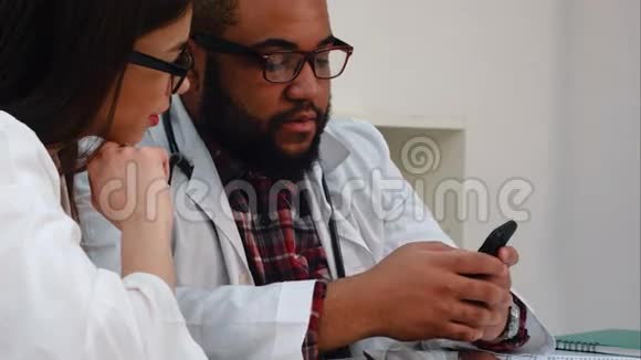 非裔美国人医生在电话里向漂亮的女同事展示一些东西视频的预览图