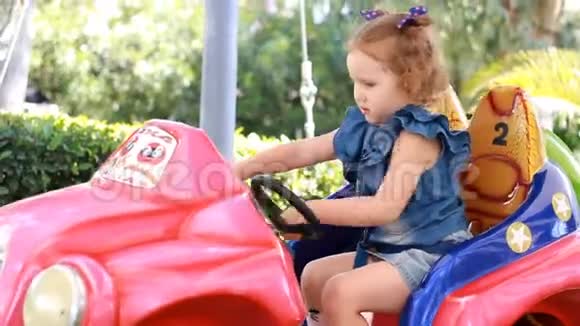 小女孩和骑电动汽车在公园娱乐视频的预览图