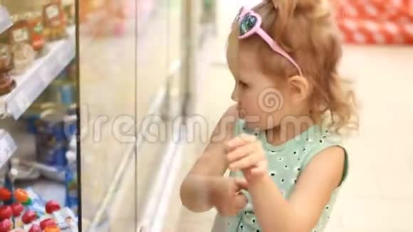 商店里的小女孩打开冰箱门买婴儿食品在超市购物视频的预览图