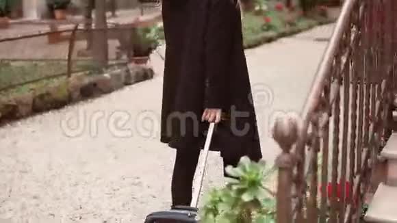 黑色旅游妇女的后景在街上用手提箱行走的女性腿的特写镜头视频的预览图