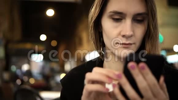 晚上坐在市中心使用带有触摸屏的智能手机的年轻严肃女人的肖像视频的预览图