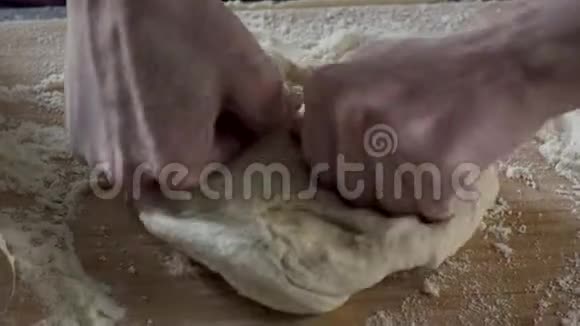 他在烤面包在面团上撒上一些面粉场景手捏面团合拢男人的手揉捏面团视频的预览图