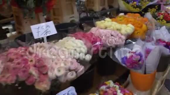 买家沿着长长的市场排走带着五颜六色的花束购物视频的预览图