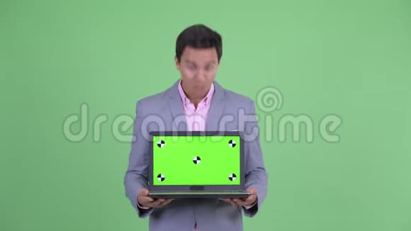 快乐年轻英俊的商人展示笔记本电脑看上去很惊讶视频的预览图