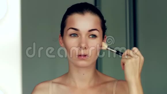 一个年轻漂亮的女孩在镜子里化妆时的倒影视频的预览图