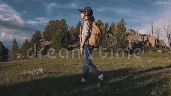 女旅行者去山里远足了一个小孩子在山路上带背包和棍子的游客慢慢慢慢视频的预览图