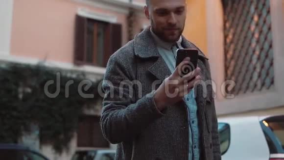 年轻人发短信在城市的smarphone上使用应用程序英俊的商人使用触摸屏技术微笑视频的预览图