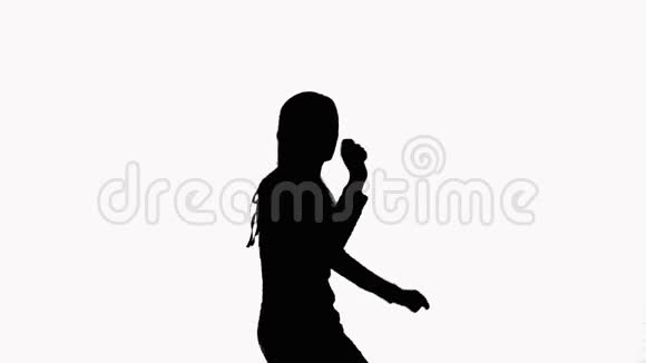 一个女孩在工作室里快乐地跳舞的剪影在白色背景上视频的预览图