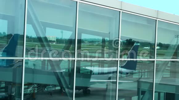 登机走道和机场区域停放的飞机反映在候机楼的窗户上视频的预览图