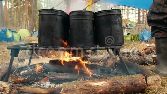 篝火上三个黑色铁锅用来煮食物视频的预览图
