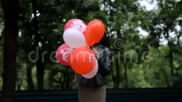 漂亮的黑发女人站在街上留着许多彩色气球视频的预览图