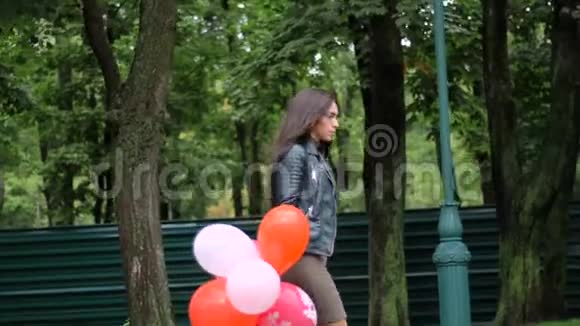 美丽的女孩走在五颜六色的气球上视频的预览图