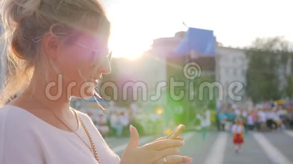 可爱的女孩手臂上有手机特写毛茸茸的女人拿着小玩意站在市中心视频的预览图