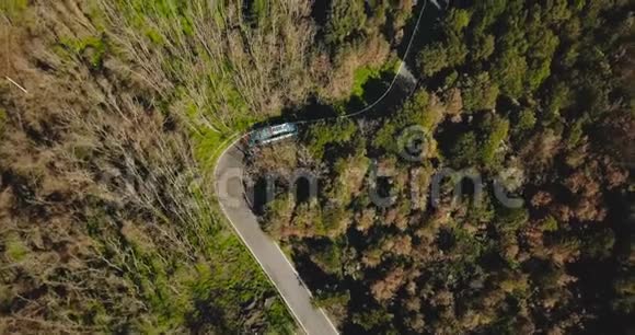 无人机跟随蓝色公共汽车沿着山路行驶非常狭窄的森林车道的鸟瞰图旅游和旅游4K视频的预览图