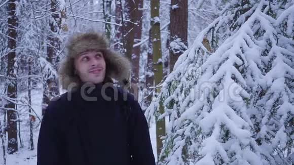 快乐的人走在白雪覆盖的寒冷的冬天森林里视频的预览图