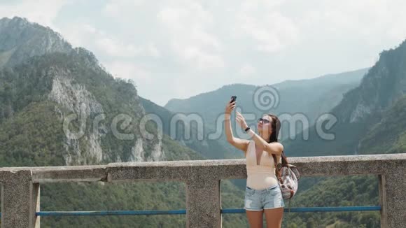 在黑山通过桥上的电话来实现自我的旅游女孩视频的预览图